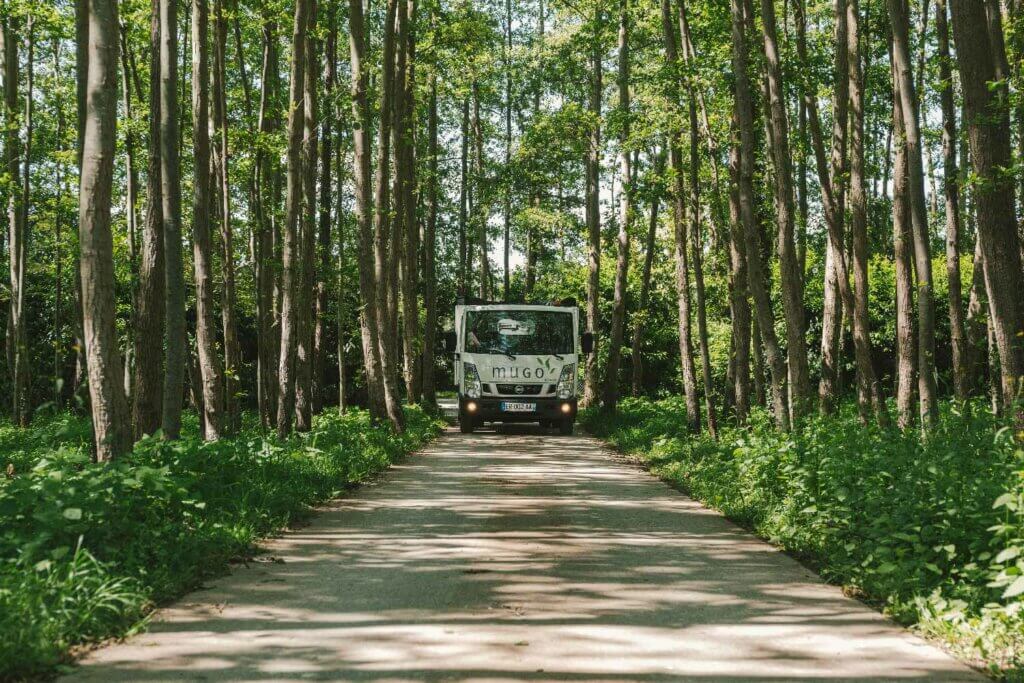 Camion MUGO dans une allée d'arbres